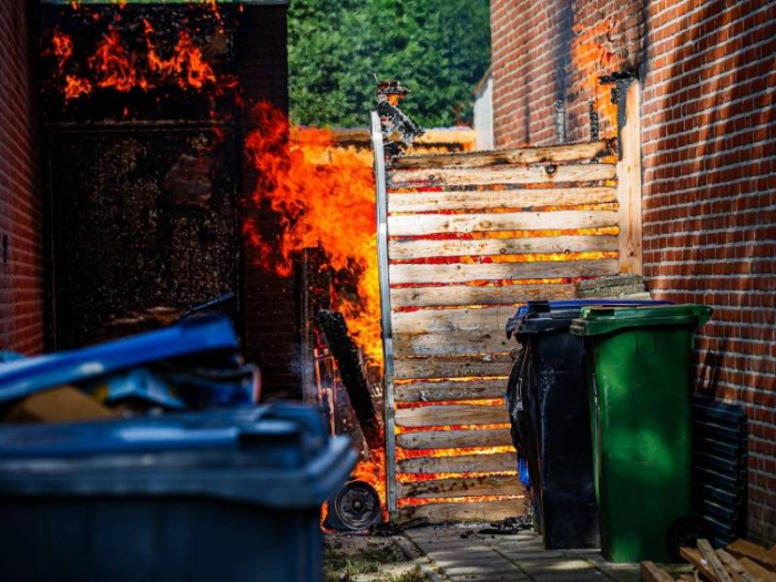Uitslaande brand tussen woningen verwoest schutting, persoon ademt rookt in